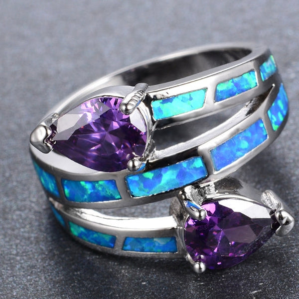 Silver ring with purple heart-shaped stones and blue opal inlay on a gray background